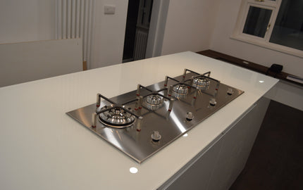 Modern kitchen with sleek white glass countertop and stainless steel gas hob