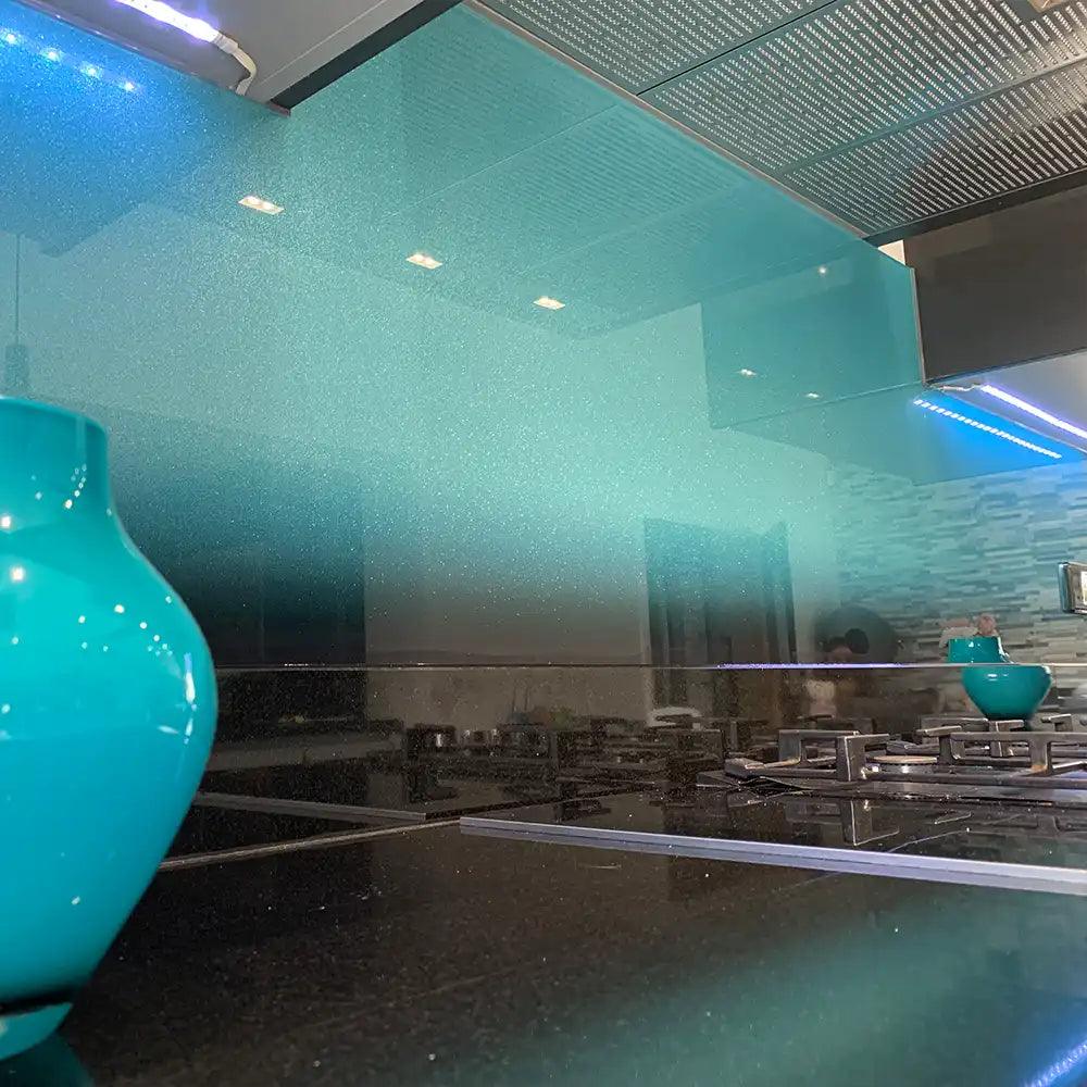 Turquoise LED backlit glass splashback in modern kitchen with reflective countertop