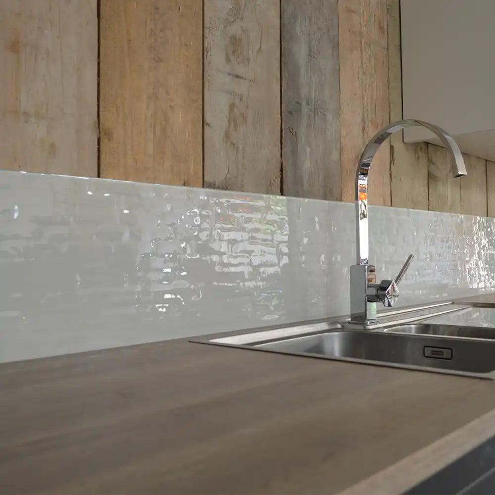 Textured glass kitchen splashback with wooden panel backdrop and chrome faucet
