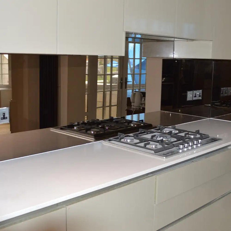 Modern kitchen with sleek glass splashback and gas hob, reflecting windows and luxury interior design