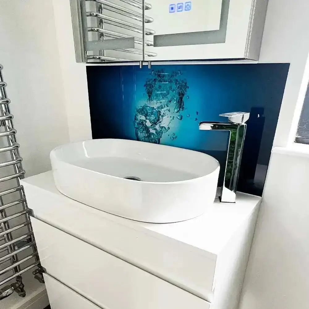 Blue decorative glass splashback with water design behind white basin in modern bathroom