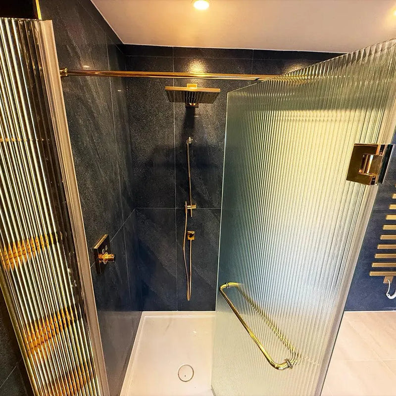 Luxury shower with textured glass panels and gold fixtures, featuring bespoke architectural glass design