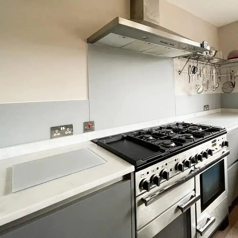 Sleek grey glass kitchen splashback behind stainless steel range cooker and hood