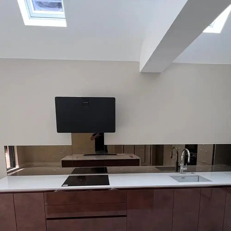Modern kitchen with sleek glass backsplash, skylights, and integrated appliances for luxury residential design