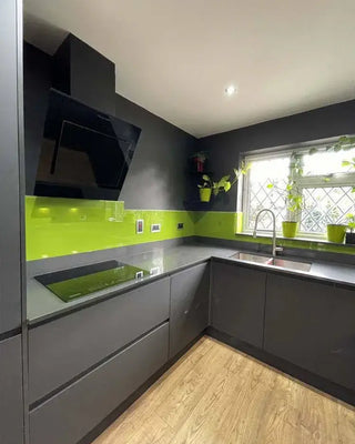 Modern kitchen with lime green glass splashback, grey cabinets, and wooden flooring