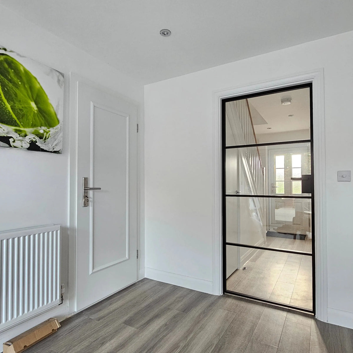 Modern black-framed glass door in a bright hallway, showcasing sleek architectural glass design for luxury homes.