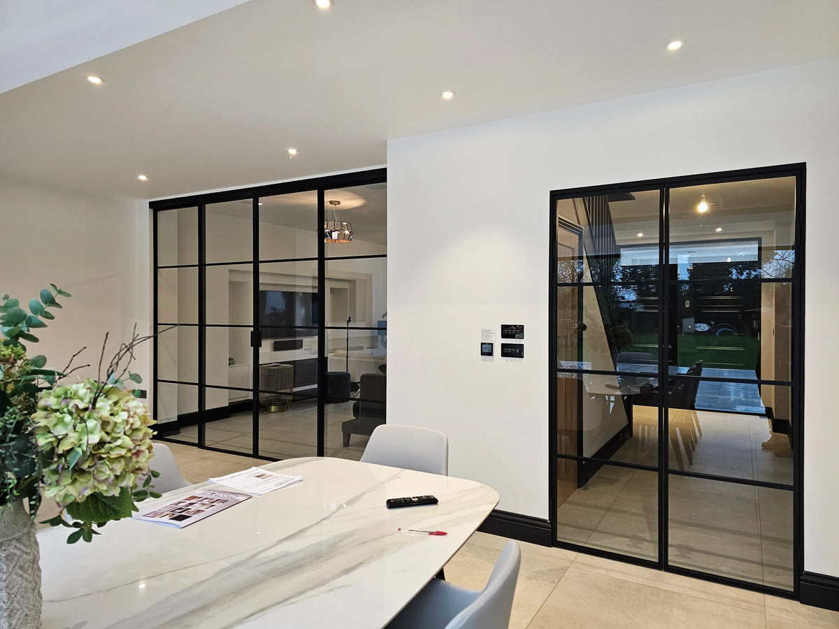 Modern black-framed glass partition walls in a luxury home, separating dining and living areas with sleek design.