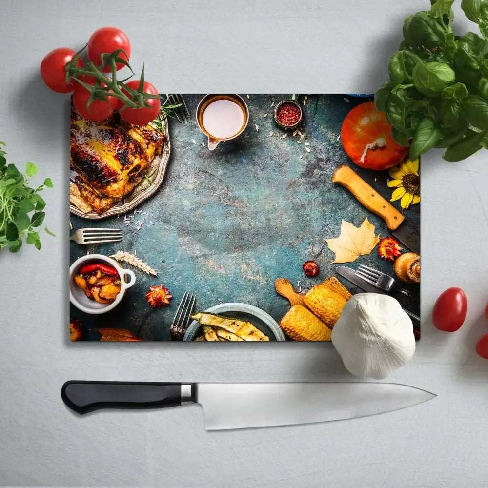 Glass cutting board with food print, surrounded by tomatoes, basil, and kitchen tools