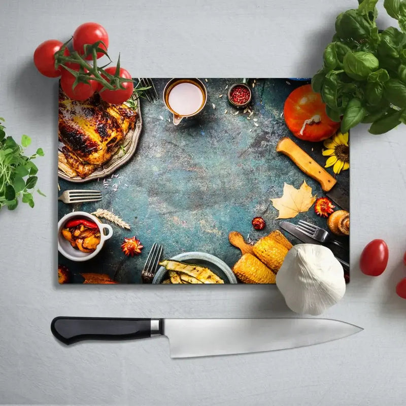 Glass cutting board with food print, surrounded by tomatoes, basil, and kitchen tools