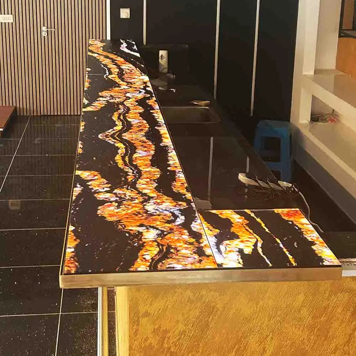 Bespoke LED backlit glass countertop with vibrant amber and black marbled pattern for luxury interiors