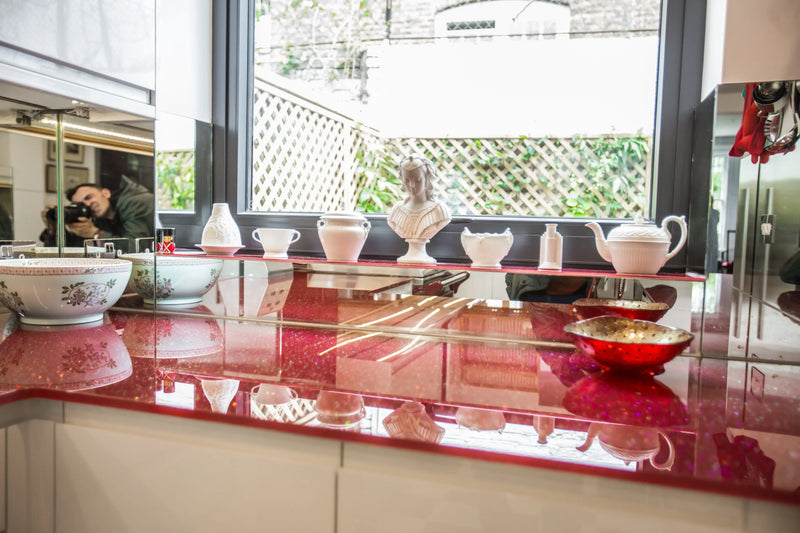 Bespoke red glitter glass shelving with decorative porcelain and mirrors, perfect for luxury interiors.