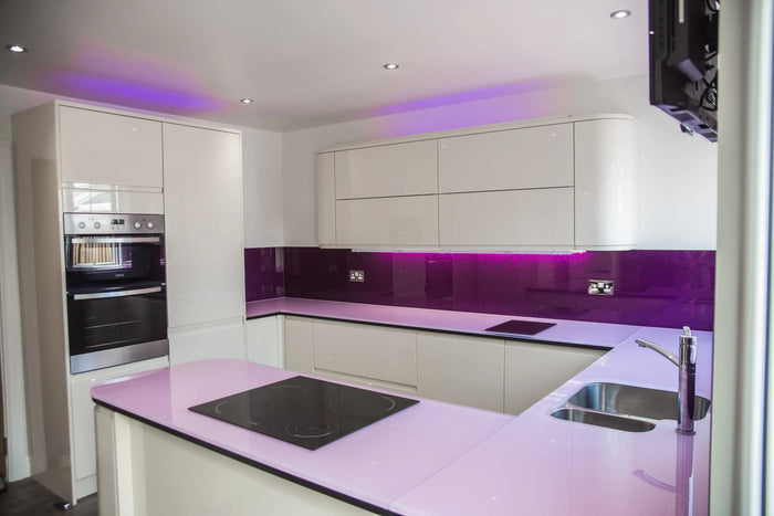 Modern kitchen with purple LED backlit glass splashback and glossy white cabinets