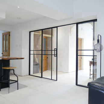Modern interior with black metal-framed double glass doors and side panels in white room