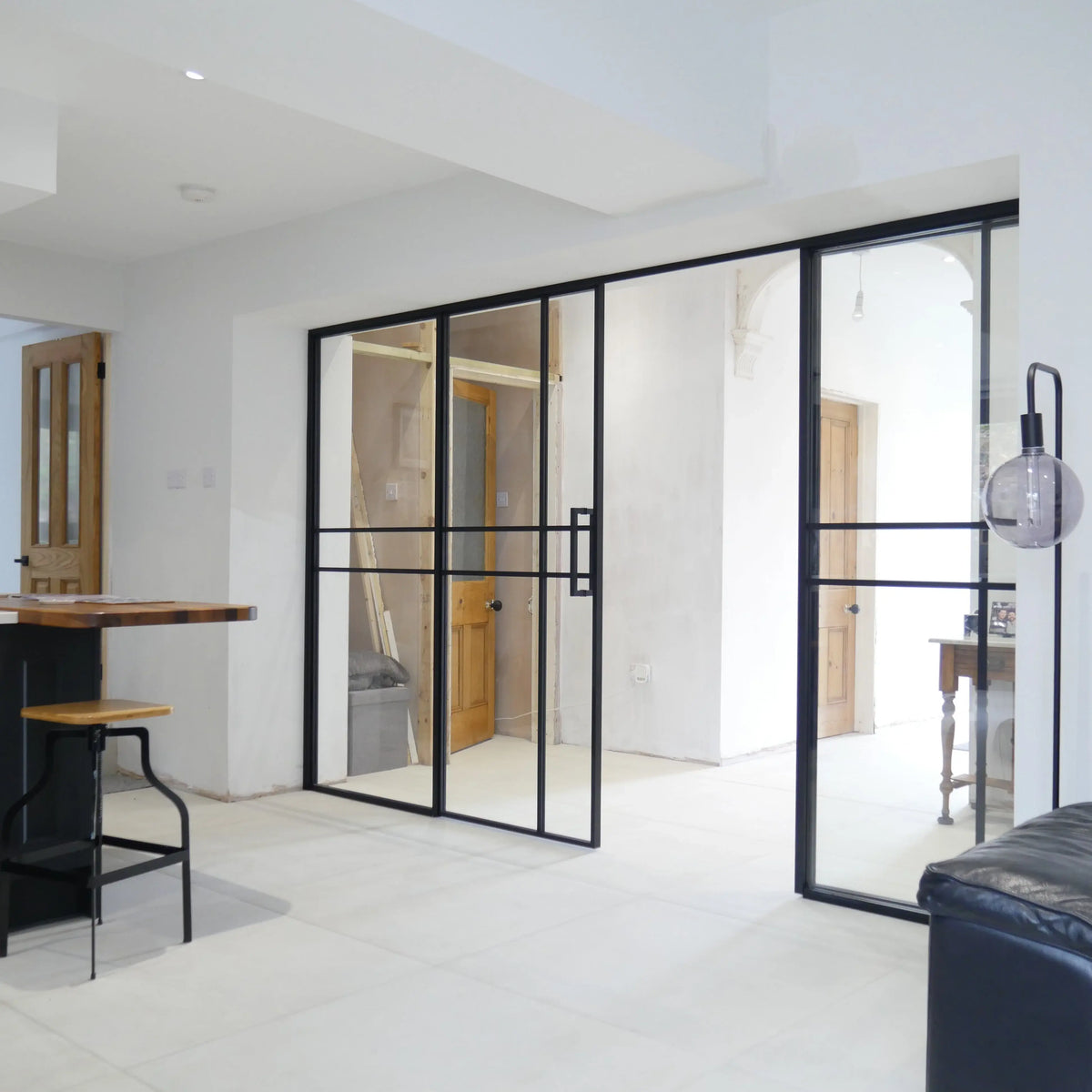 Black-framed glass partition doors in modern home, featuring sleek sliding design and minimalist aesthetic for luxury residential spaces.
