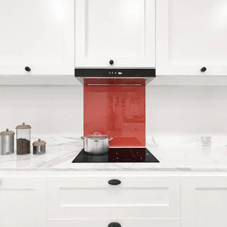 Vibrant red glass splashback in modern white kitchen with marble countertop and induction hob