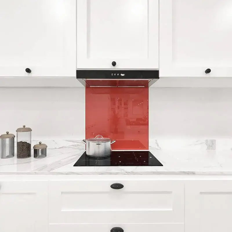 Vibrant red glass splashback in modern white kitchen with marble countertop and induction hob