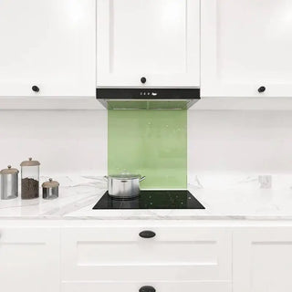 Green glass splashback in modern white kitchen with marble countertop and induction hob