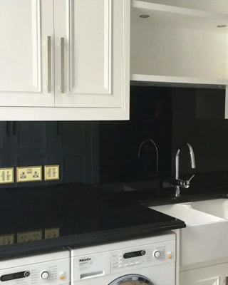 Black glass splashback in modern kitchen with white cabinets and Miele appliances