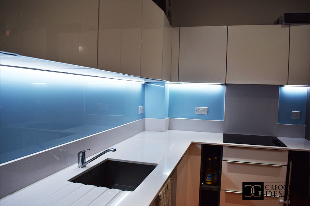 Modern kitchen with blue LED backlit glass splashback and sleek white countertops