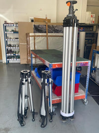 Three tripods in workshop with glass panels and storage shelves