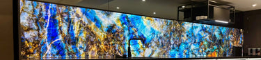 Large digital display with abstract blue and gold design in a room setting.