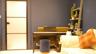 Modern room with a digital piano, blue walls, a frosted glass hinged door, and decorative shelving