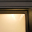 Close-up of a hinged door frame with frosted glass and matte black metal edging