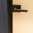 Modern black metal hinged door handle on frosted glass panel door with blue frame