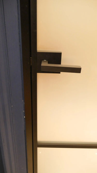Modern black metal hinged door handle on frosted glass panel door with blue frame