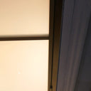 Close-up of a hinged frosted glass door with dark metal frame and blue door trim on tiled floor