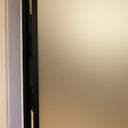 Close-up of a frosted glass hinged door with black metal frame inside a beige wall frame