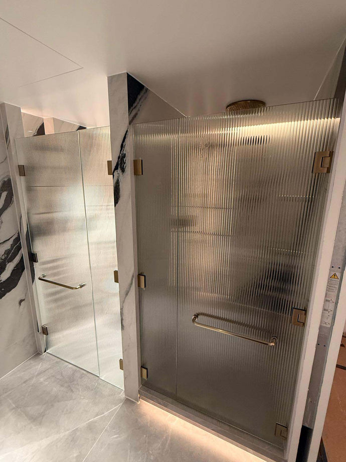 Ribbed glass shower doors with brass hardware at Portman Towers