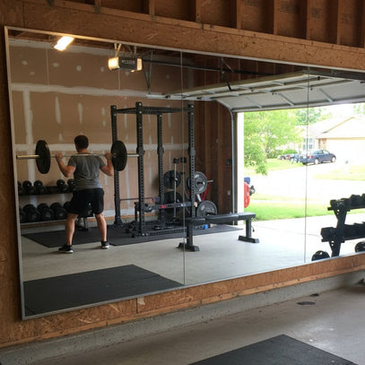 Home gym with weights and a large mirror reflecting the interior.