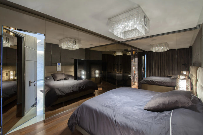 Modern bedroom with large mirror, bed, and decorative lighting.