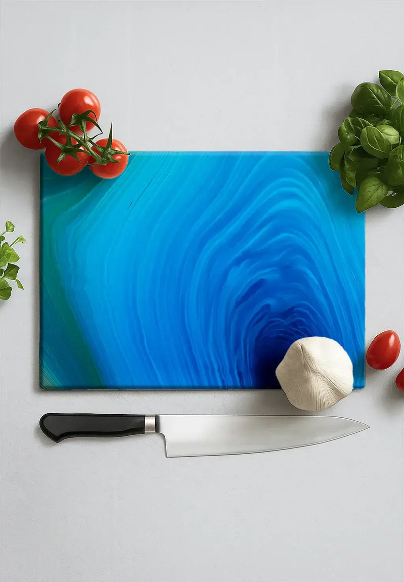 Blue agate design glass chopping board with tomatoes, basil, garlic, and chef knife on white surface